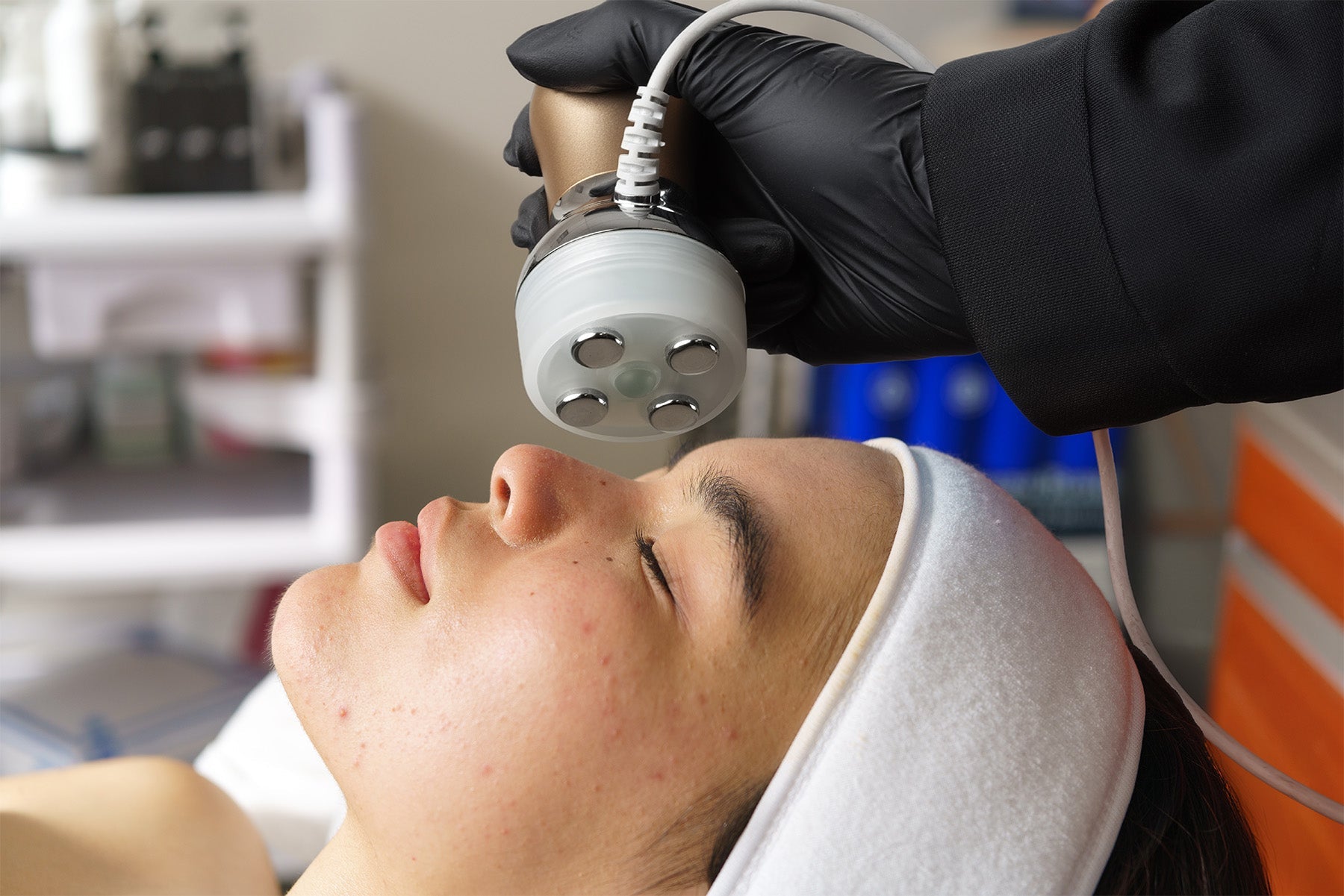 Professional esthetician performing advanced facial treatment using skincare device during online esthetician training course