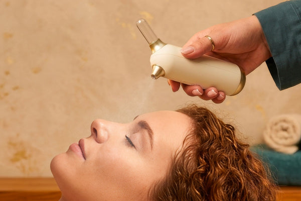 Person receiving a head massage with a handheld device in a spa setting.